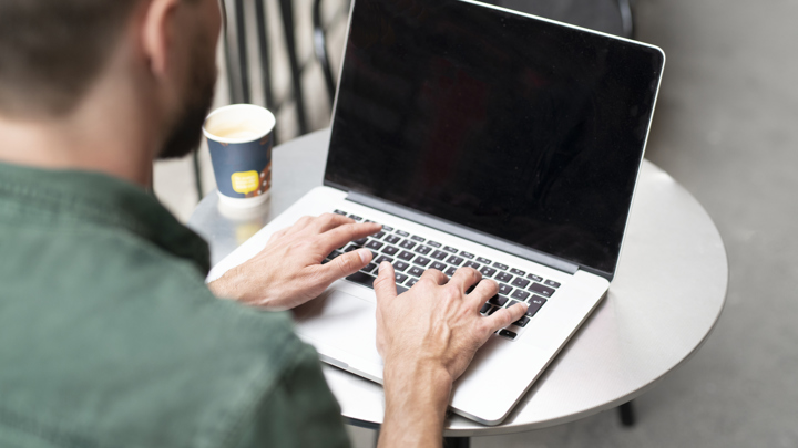 Bild på person som sitter framför en bärbar dator. 