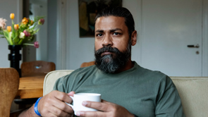 Man i hemmet som håller en mugg.