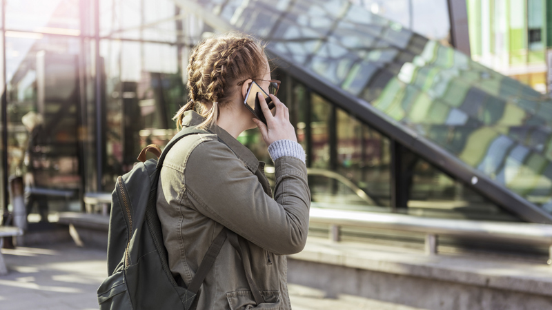 Tjej pratar i mobiltelefon i stadsmiljö.