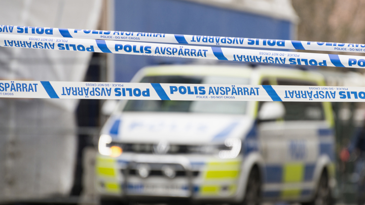 Band som visar att ett område är avspärrat område och en polisbuss i bakgrunden.